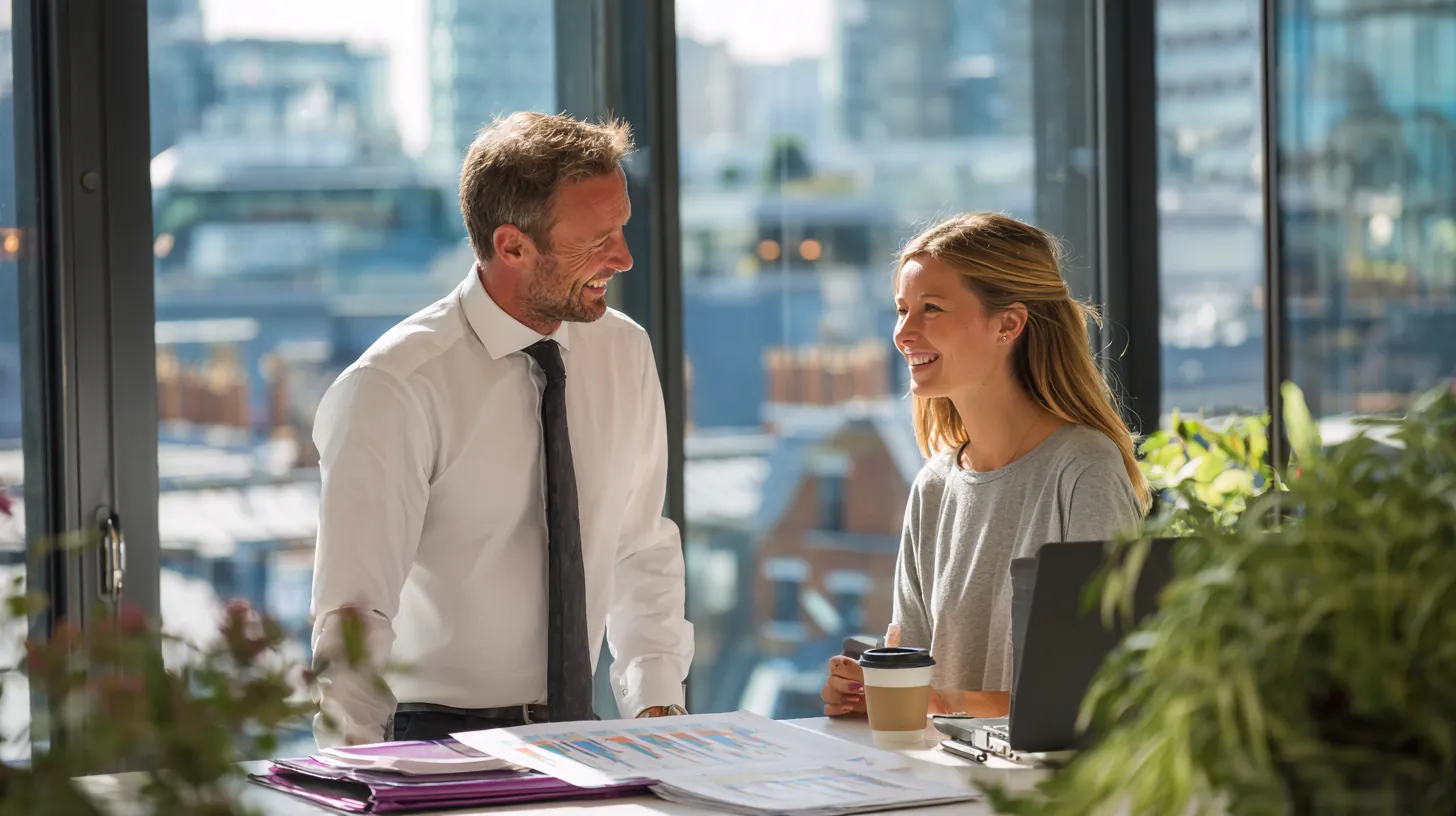 Analyst laying a printed chart on a standing desk, colleague handing her a coffee